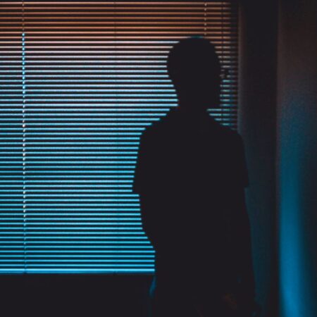 Man in a dark room looking at mirror